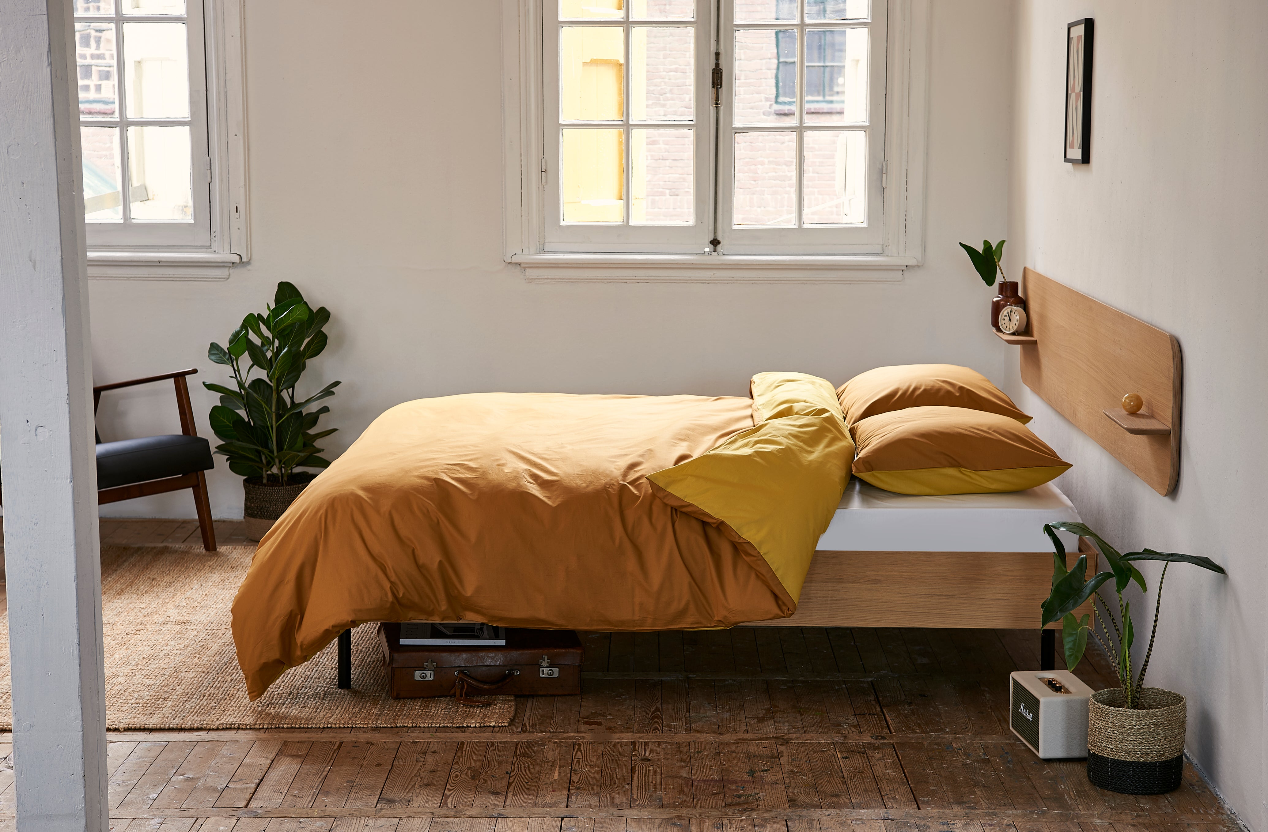 Losjes opgemaakt bed met gele en witte kussens en dekbedovertrek